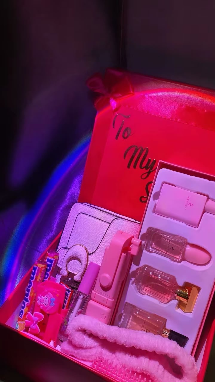 Pink romantic surprise box filled with perfumes, a purse and treats under soft neon light